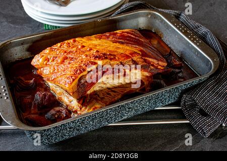 Frisch gekochtes Schweinebraten mit Kruste auf einem Backblech serviert auf einem Tisch. Bereit zum Essen Stockfoto