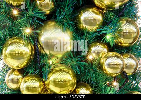 Goldene Kugeln und Kugeln hängen als Dekoration auf einem Weihnachtsbaum, Nahaufnahme Stockfoto