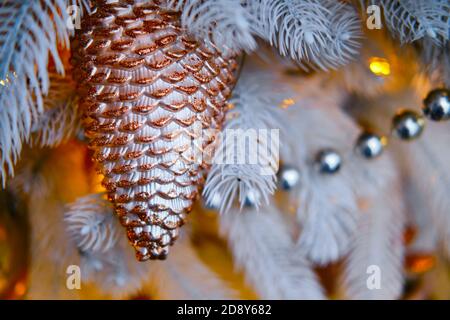 Goldkegel und Perlen hängen als Dekorationen an einem Weihnachtsbaum, Nahaufnahme Stockfoto