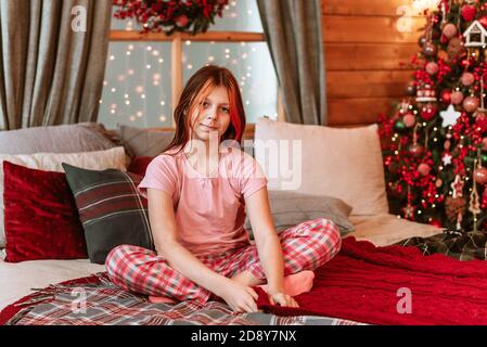 Teenager Mädchen in Pyjama auf dem Bett mit Spaß auf Weihnachtsmorgen Stockfoto