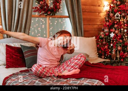 Teenager Mädchen in Pyjama auf dem Bett mit Spaß auf Weihnachtsmorgen Stockfoto