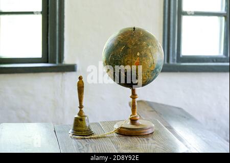 Ein alter Globus, der auf einem Tisch vor dem Hintergrund des Klassenraums liegt. Retro-Style. Wissenschaft, Bildung, Reisen, vintage background. Bildungsgeschichte und g Stockfoto