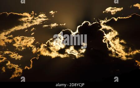 Sonnenuntergang mit Sonne hinter tiefen Wolken, die Formen brillante Konturen verleihen. Frühling, Queensland, Australien. Hintergrund, Kopierbereich. Stockfoto