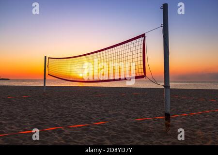Volleyballnetz am tropischen Strand und goldener Meeresaufgang Stockfoto