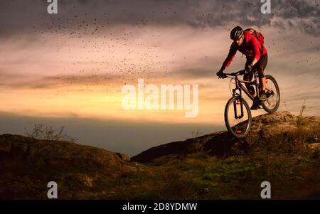 Radler in Red Riding Bike auf dem Herbst Rocky Trail bei Sonnenuntergang. Extreme Sport und Enduro Biking Konzept. Stockfoto