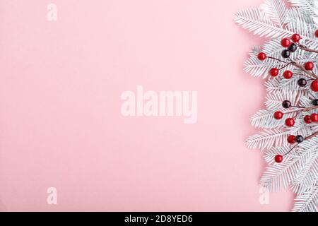 Weihnachtliche Umrandung mit Tannenzweigen, Eberesche und goldenen Lichtern auf pastellrosa Hintergrund Stockfoto