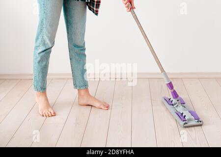 Das Konzept der Reinigung. Frau in legerer Kleidung waschen Fußböden. Im Hintergrund ist eine weiße Wand. Nahaufnahme. Stockfoto