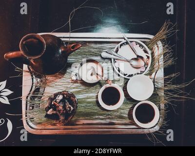Mit Tassen äthiopischen Kaffee serviert mit aromatischer Essenz. Weihrauch und Myrrhe, die durch eine heiße Kohle entzündet werden, um Rauch zu erzeugen, der irgendeinen wegträgt Stockfoto