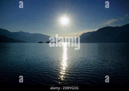 Sonnenstrahl über einem alpinen Lago Maggiore mit Brissago Inseln und Berg im Tessin, Schweiz. Stockfoto