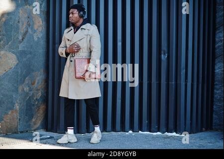 Afroamerikanischer Mann mit Kopfhörern, tragen Hut und Mantel hören Musik auf Stahl Hintergrund. Stockfoto