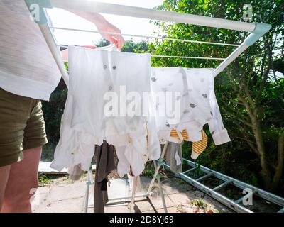 Low-Winkel-Ansicht einer schwangeren Frau Kind Körper und Schlafanzug zum Trocknen im Garten Stockfoto