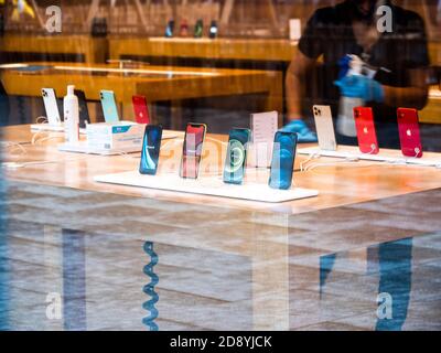Paris, Frankreich - 23. Okt 2020: Silhouette der Arbeiterinnen Reinigung mit Alkohol Handgel Desinfektionsmittel das neue iPhone 12 und iPhone 12 Pro wird während des Einführungstages im Apple Store ausgestellt. Die neuesten 5G-Smartphones sind weltweit erhältlich. Stockfoto