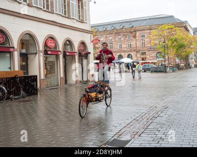 Paris, Frankreich - 23. Okt 2020: Mann auf einem großen seltsamen Fahrrad im Zentrum von Straßburg an einem regnerischen Tag Stockfoto