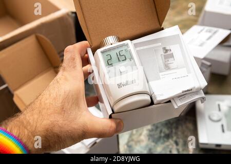 Paris, Frankreich - Oct 25, 2020: POV männliche Hand zeigt ein ausgepacktes Paket von Vaillant Ambisense VR50 Thermostat-Ventil angeschlossen IoT-Gerät an den Gas-Heizungspumpe Kessel - Paket mit Bedienungsanleitungen Stockfoto