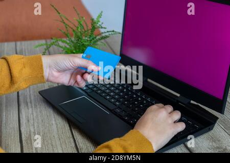 Frau Hände halten eine Kreditkarte und Tastatur Laptop eingeben, mit mockup rosa leeren Bildschirm.Making Online-Zahlung, Shopping oder Banking, E-Commerce-con Stockfoto