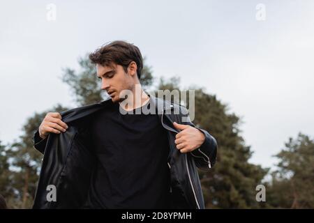 Junge Brünette Mann trägt Lederjacke im Freien Stockfoto