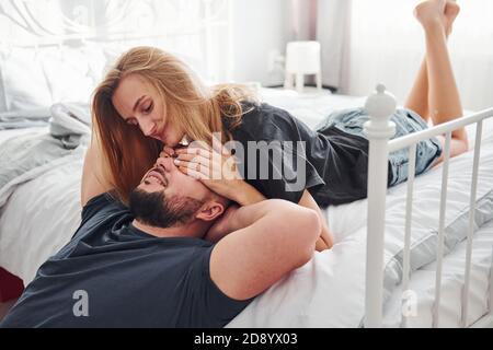 Junge verheiratete Paar küssen sich gegenseitig im Schlafzimmer am Tag Stockfoto