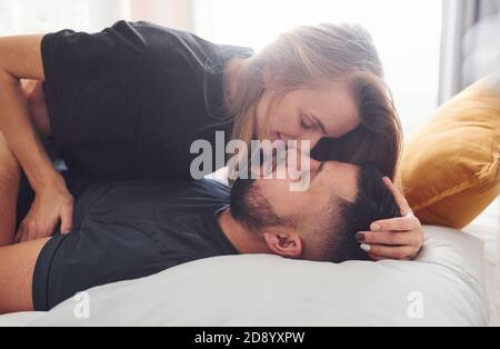 Junge verheiratete Paar küssen sich gegenseitig im Schlafzimmer am Tag Stockfoto