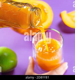 Obst Kürbis Apfel Karotte Ingwer auf farbigem Hintergrund Hände Saft Lecker Stockfoto