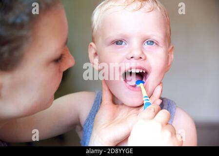 Mama lehrt und hilft ihrem dreijährigen Sohn, seine Zähne aus nächster Nähe zu putzen. Stockfoto