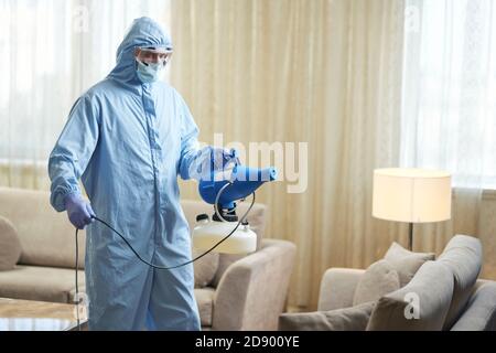 Arbeiter trägt Schutzkleidung und desinfiziert eine Hotel-Wohnung Coronavirus Und Quarantänekonzept Stockfoto