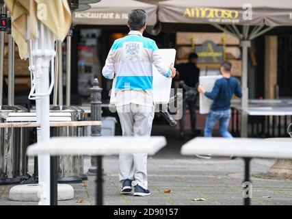 02. November 2020, Hessen, Frankfurt/Main: Mitarbeiter des Restaurants "Amoroso" am Frankfurter Opernplatz räumen die Tische des Outdoor-Restaurants ab. In ganz Deutschland hat eine vierwöchige Teilsperre begonnen, um die Ausbreitung des Corona-Virus zu verlangsamen. Foto: Arne Dedert/dpa Stockfoto