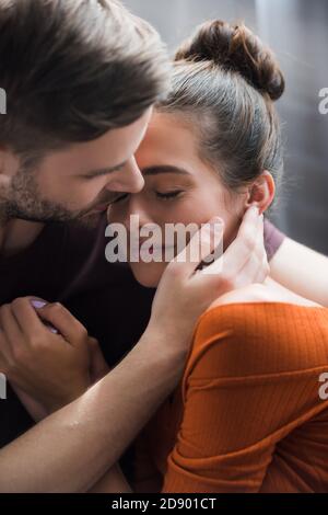 Zärtlicher Mann umarmte und berührendes Gesicht der depressiven Freundin an Zu Hause Stockfoto