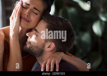 Weinende Frau berührt Gesicht, während geliebten Mann zu Hause umarmt Stockfoto