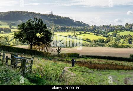 Wanderer auf dem Cotswold Way in der Nähe von North Nibley in der Gloucestershire Cotswolds auf dem Weg zum Tyndale Monument in der Ferne Stockfoto