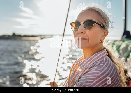 Porträt einer reifen Frau trägt Sonnenbrille auf einem stehen Segelboot und Blick in die Ferne Stockfoto