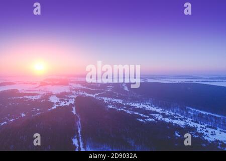 Luftaufnahme der Morgen Blick auf die Landschaft. Schneebedeckte Felder und Pinienwald bei Sonnenaufgang Stockfoto