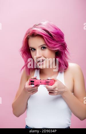 KIEW, UKRAINE - 29. JULI 2020: Junge Frau mit bunten Haaren halten Joystick isoliert auf rosa Stockfoto