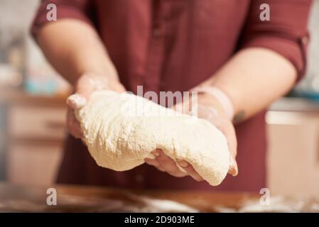 Weibliche Hände halten den fertigen rohen Teig aus der Nähe Stockfoto