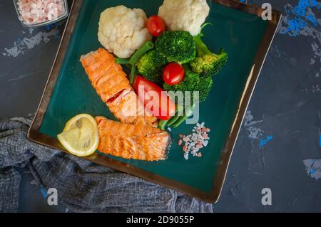 Diät Servieren von Lachs mit Zitrone, Brokkoli und Gemüse. Zwei Stücke gegrillter Lachs werden auf einem schönen Teller serviert Stockfoto