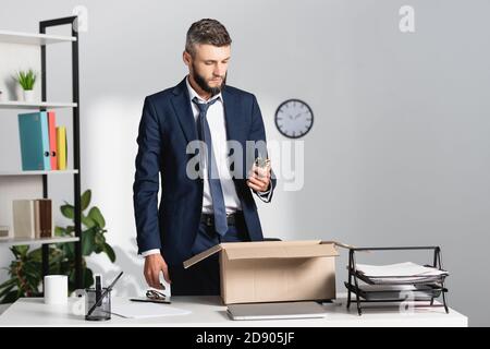 Entlassene Geschäftsmann Holding-Werk in der Nähe Laptop, Schreibwaren und Karton auf Tisch im Büro Stockfoto