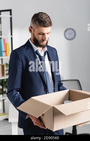 Trauriger Geschäftsmann hält Karton im Büro Stockfoto