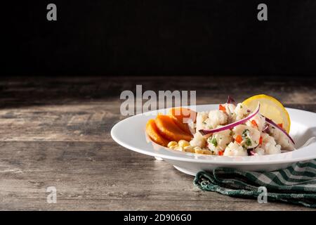 Traditionelle peruanische Ceviche mit Fisch, Süßkartoffeln, Mais und Gemüse auf Holztisch Stockfoto