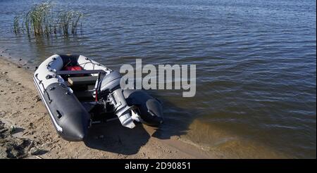 Schlauchboot mit Außenbordmotor am Sandstrand vorbei Fluss Stockfoto