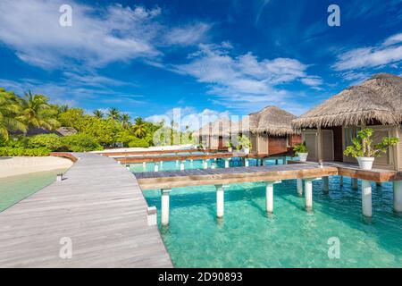 Water Villas Bungalows auf der perfekten tropischen Insel, wunderschöner weißer Sand am tropischen Strand blaues Wasser blauer Himmel mit Kokospalmen, Malediven Inseln Stockfoto