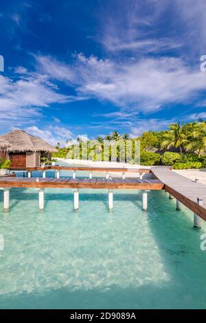 Water Villas Bungalows auf der perfekten tropischen Insel, wunderschöner weißer Sand am tropischen Strand blaues Wasser blauer Himmel mit Kokospalmen, Malediven Inseln Stockfoto