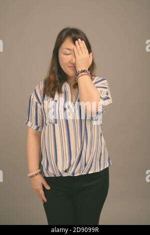 Reifen schöne asiatische Geschäftsfrau gegen grauer Hintergrund Stockfoto