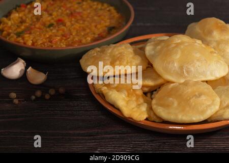 Indische Küche. Luchi Tortillas mit gekochtem und frischem Gemüse, Halwa Puri oder Shira Poori. Holzhintergrund. Stockfoto