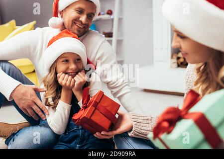 Mutter in santa hat Geschenk zu glücklichen Tochter in der Nähe Vater Stockfoto