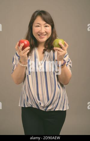 Reifen schöne asiatische Geschäftsfrau gegen grauer Hintergrund Stockfoto