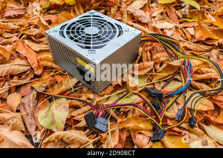 Eine Dump von alten Computer-Ausrüstung, unter denen liegt ein Kaputtes Netzteil im Herbstlaub Stockfoto