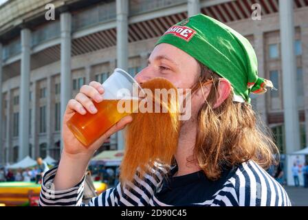 Junger Mann mit rotem Bart trinkt Bier aus einem Plastikglas beim internationalen Bierfest. Moskau, Russland, 09.07.2009 Stockfoto