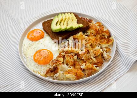 Leckere hausgemachte gebratene Hashbrowns und Eier auf einem Teller, Blick aus der unteren Ecke. Stockfoto