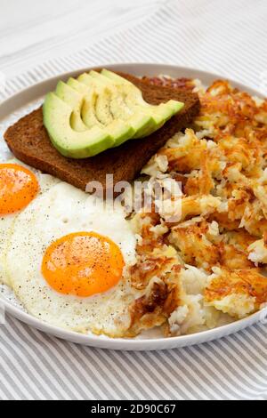 Leckere hausgemachte gebratene Hashbrowns und Eier auf einem Teller, Seitenansicht. Stockfoto