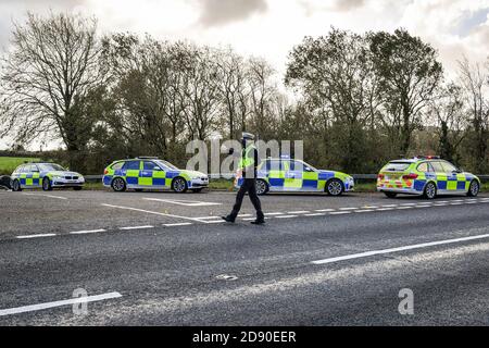 Walisische Polizei zieht Autos an einem Kontrollpunkt während Feuerbremsfahrzeuge Patrouillen nahe der Grenze zwischen Camarthenshire und Pembrokeshire, Wales. Erster Minister Mark Drakeford wird am Montag neue nationale Coronavirus-Maßnahmen für Wales vorstellen. Stockfoto