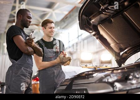 Zwei freundliche professionelle Auto-Mechaniker während der Arbeit, sind sie erfolgreich Reparatur Auto, lösen Probleme zusammen Stockfoto